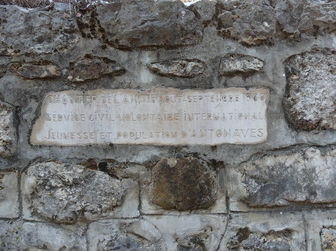 Rue de la Calade, mur de soutènement portant une pierre gravée rappelant le chantier du Service Civil Volontaire International en 1960.