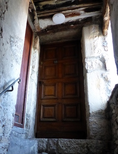 Extension de logis au-dessus de la rue, rez-de-chaussée surélevé. Vestibule, porte du logis.