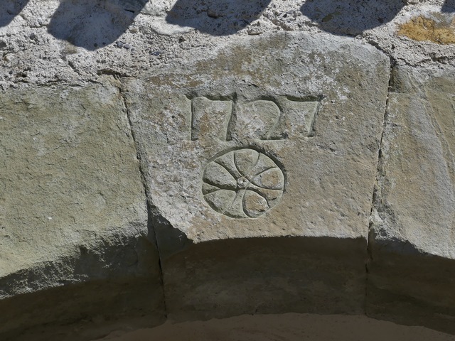 Portail nord-ouest. Clef de l'arc plein-cintre, portant la date gravée 1727 accompagnée d'une rosace.