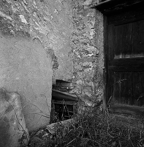 Mur gouttereau nord : la porte de la chambre ménagère. La fenêtre de l'écurie de la maison voisine est profondément enterrée dans le sol.