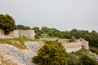 Front de gorge de l'ouvrage,  mur d'enceinte à deux saillants flanquants, ruines du baraquement crénelé hors enceinte, vus de l'extrémité de la terrasse.