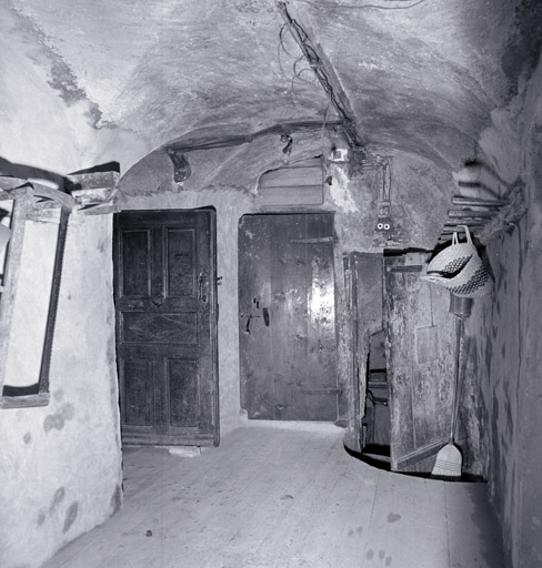 Partie A. Rez-de-chaussée. Vue d'ensemble prise depuis la porte d'entrée. De gauche à droite : porte de la cuisine, de l'escalier et de la cave.
