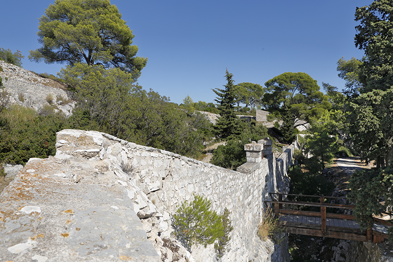 Alignement du front de gorge de l'enceinte et de son fossé, avec la porte de l'ouvrage, vus de l'est du chemin de ronde.