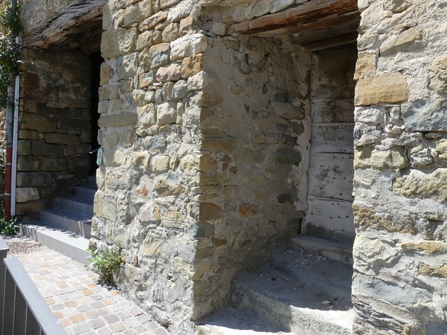 Courtine est. Maçonnerie de l'enceinte fortifiée, percée par une porte de cellier et par le passage couvert du Portallet.