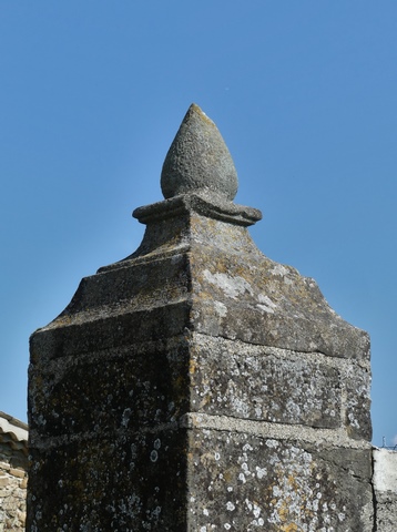 Cour. Mur de clôture, pilier avec couvrement sculpté.