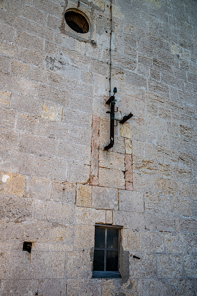 Détail extérieur de la face nord de la tour : au 1er étage, vestiges remaniés de l'ancienne porte à pont-levis à deux flèches, transformée en fenêtre