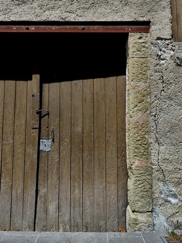 Encadrement de porte avec piédroits en pierre de taille et couvrement en poutrelle métallique, entrepôt agricole au bourg.