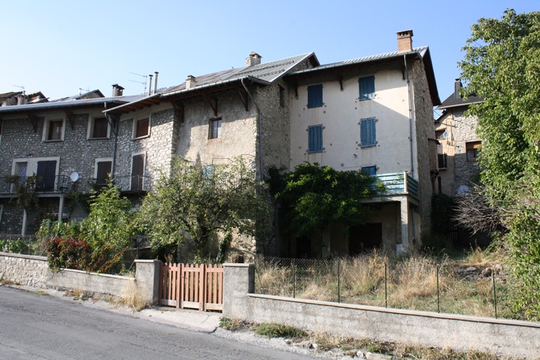 Le Village. Maisons en léger retrait de la route départementale 2 à l'extrémité est du village. L'aménagement de la route départementale 2 a entraîné une modification de leur orientation. La façade postérieure est devenue façade principale, avec balcons voire terrasse au sud, tournant le dos à la Grande Rue délaissée.