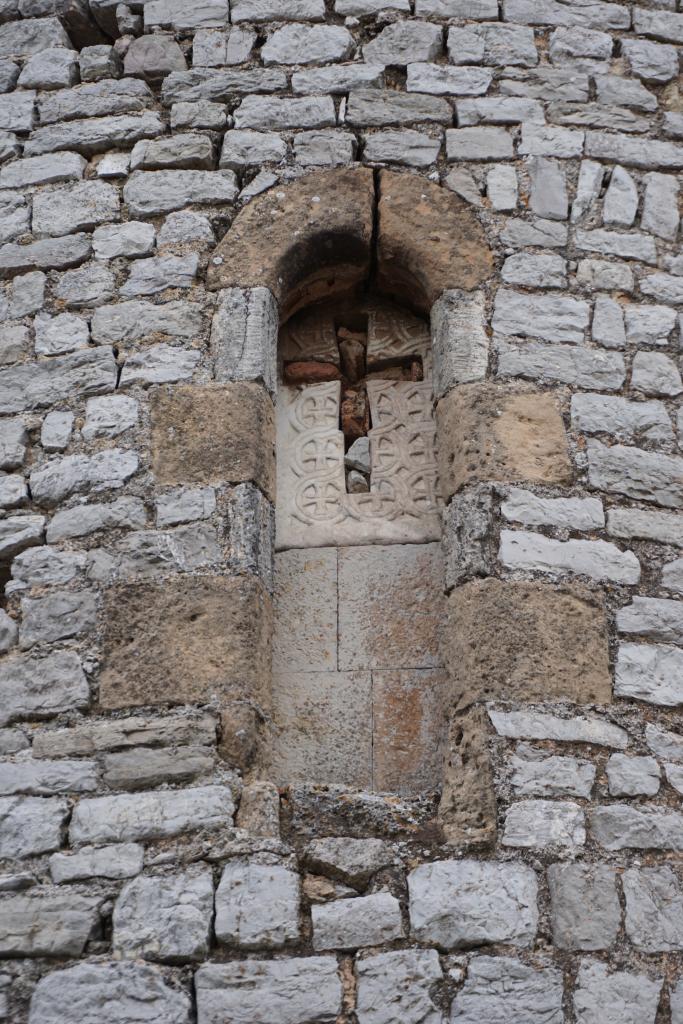 Détail de l'abside : baie axiale avec plaque de chancel en remploi.