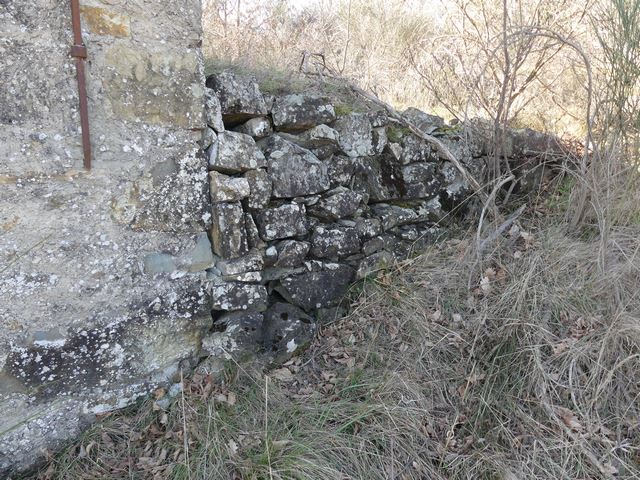 Plate-forme aménagée devant l'élévation nord. Mur de soutènement en pierre sèche.