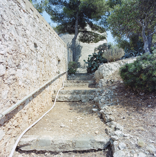 Mur de clôture crénelé de l'enceinte et chemin de ronde montant vers la tour.