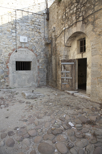 Angle sud-est de la cour, arcade murée du sas du magasin à poudre, arcade de casemate, pavé.