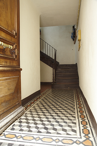 Rez-de-chaussée surélevé. Entrée de la maison avec couloir recevant un sol recouvert de carreaux de ciment teinté dans la masse et départ de l'escalier tournant en fond de parcelle.