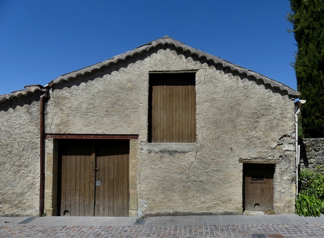 Façade en pignon d'un entrepôt agricole, au bourg.
