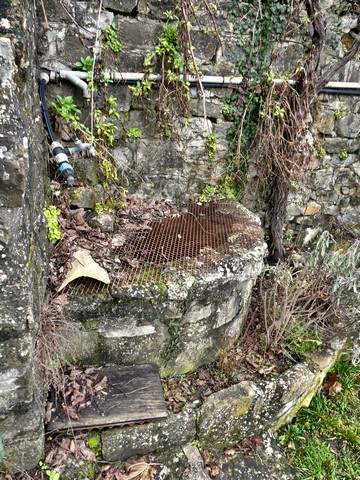 Petit bassin d'arrosage maçonné, dans le jardin d'un entrepôt agricole au bourg.