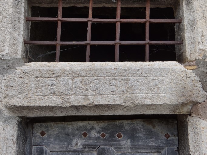 Porte de logis avec encadrement chanfreiné surmonté d'un jour sur traverse, laquelle porte la date gravée 1682 accompagnée des initiales P P. Maison située rue des Granges au bourg de Ribiers (parcelle 1998 E2 730).