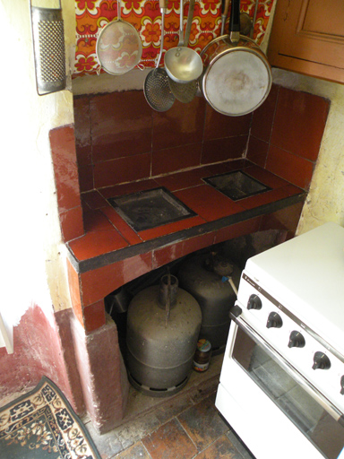 Potager à deux grilles et carreaux de terre cuite vernissés, situé dans la cuisine d'une maison à Vergons.