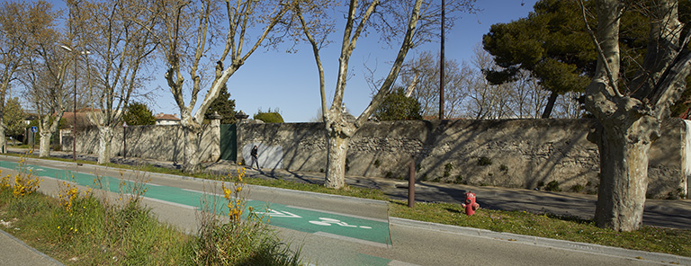 Vue du mur d'enceinte et du portail d'entrée du cimetière depuis l'ouest.