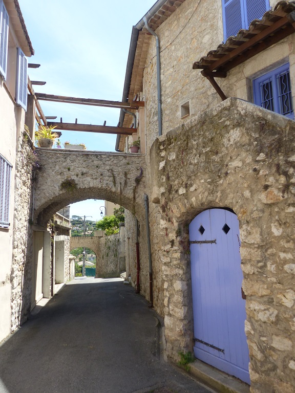 Vue d'ensemble de la rue du Pontis prise du nord, ponctuée de ponceaux reliant les parcelles bâties de part et d'autre. 