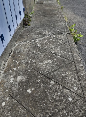 Dalle en ciment décorée, au pied du pignon nord.