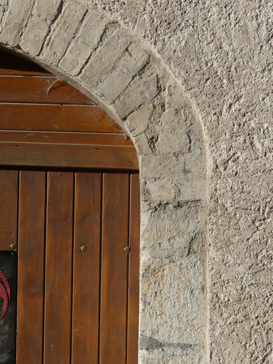 Porte de remise avec encadrement en pierre de taille et anse-de-panier en brique pleine. Bâtiment au bourg de Ribiers.