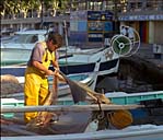 Vue prise sur le port en contrebas de la Plage de l'Estaque, pêcheur réparant un filet.