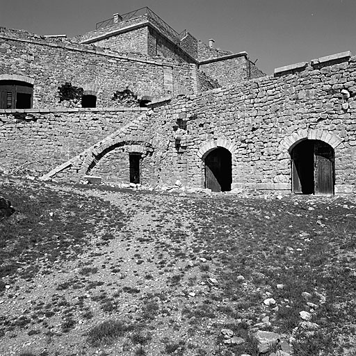 Casemate K : façade sud-ouest : remarquer les désordres produits, semble-t-il, par les essais de tir des canons de 138 de la batterie supérieure, en 1881, et une secousse sismique en 1884. A gauche, escalier sur arc rampant menant à la batterie supérieure, et couvrant le bâtiment D1 (latrines), partie droite de la casemate E et rampe d'accès à la batterie de 138. Au-dessus et à l'arrière plan, angle sud-ouest de la casemate B.