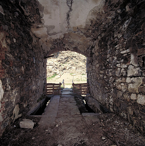 Passage d'entrée du fort vu de l'intérieur, la porte, saignées du pont-levis au sol.