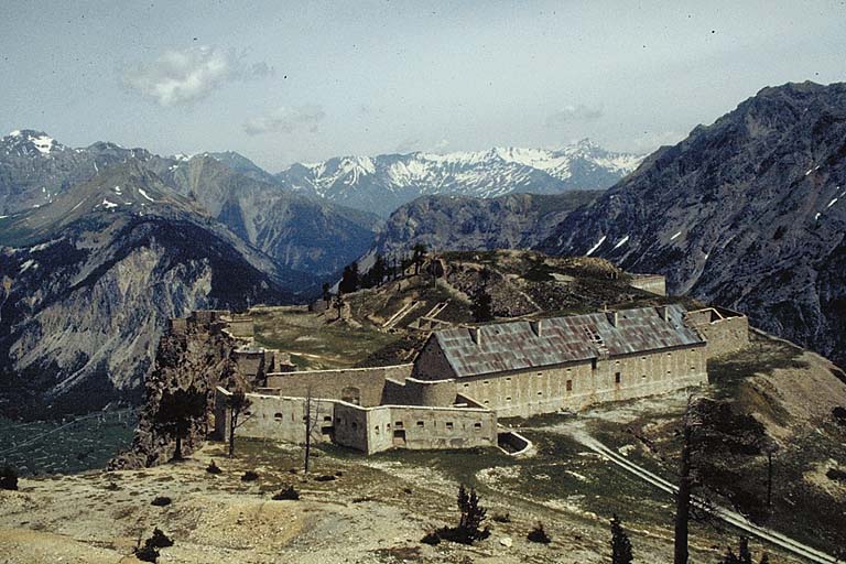 Vue d'ensemble du fort prise du sud depuis le pied des pentes de l'Enlon. Au premier plan, l' avancée couvrant l'entrée. A droite, la caserne A. Derrière, la cour centrale et le cavalier d'artillerie. Derrière le fort, la trouée du col de l'Echelle et les montagnes entourant Bardonnèche.