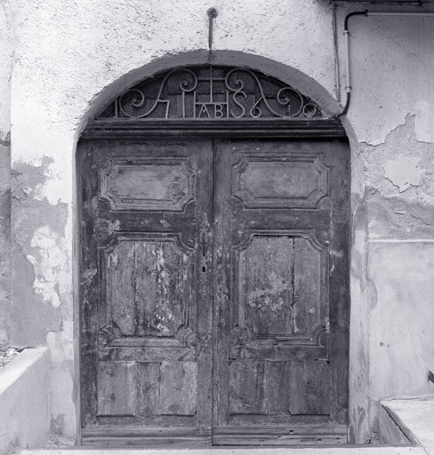 Façade antérieure sud. Corps de logis. Porte d'entrée, l'imposte en fer forgé présente le monogramme IHS, les initiales AB et la date 1760.