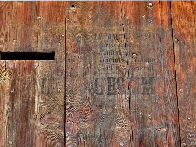 Bâtiment du logis. Pignon nord, premier niveau. Porte fenière, publicité peinte au pochoir.