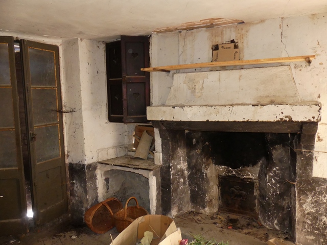 Rez-de-chaussée surélevé, cuisine. Mur ouest, cheminée et potager surmonté d'un placard mural.
