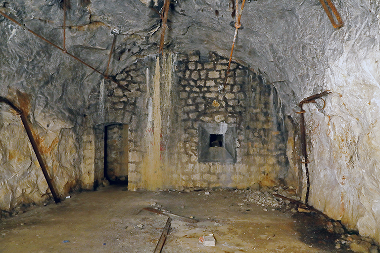  souterrain-caverne, vue intérieure du magasin-caverne à projectiles, voûte deroctée, mur du sas avec porte et créneau à lampe