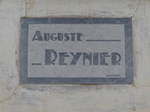 Elévation est, deuxième niveau. Plaque en calcaire avec inscription gravée « AUGUSTE REYNIER » et signature « BLINIER ».