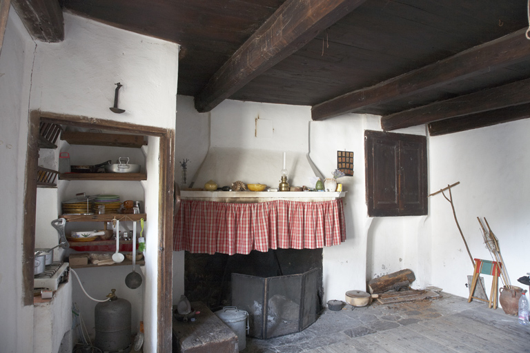 Maison à Ondres (Thorame-Haute). Pièce de logis avec cheminée et réduit séparé de l'espace principal, où prenait place une pile d'évier. Les étagères pour ranger la vaisselle sont toujours présentes en revanche. Dans la pièce, le plancher est rustique et les abords de la cheminée en dalles de pierre réfractaire.