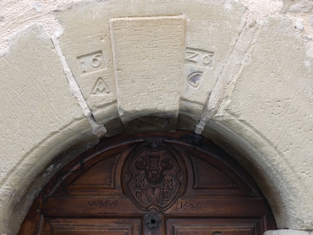 Elévation nord, premier niveau. Porte du logis, détail de la fausse agrafe passante et saillante avec date (1626) et initiales (AG).