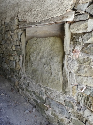 Elévation ouest, sous le passage couvert. Ouverture murée par une dalle sur chant, servant de pierre foyère à l'intérieur.