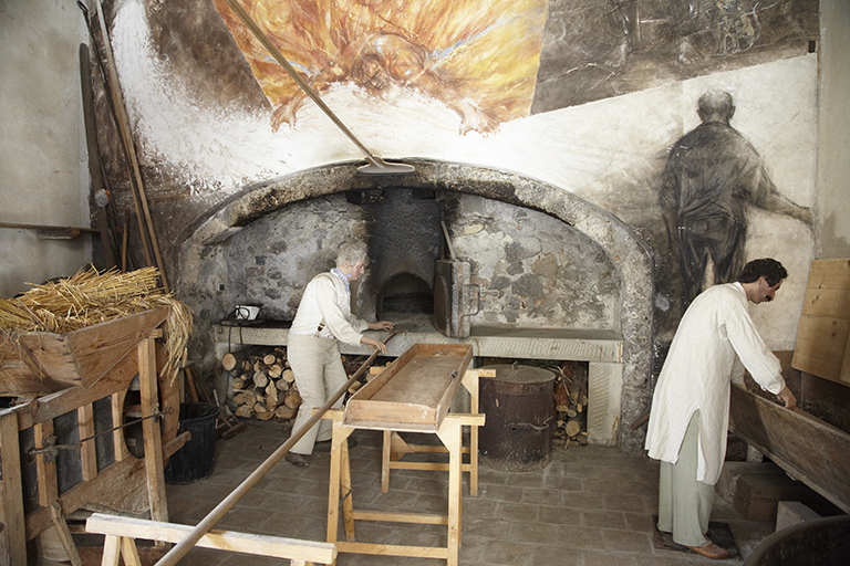 Reconstitution du four en activité pour la fête des "Médiévales". Au-dessus de la bouche du four, les fresques illustrent le cycle du blé au pain.