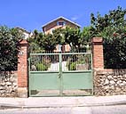 Maison au 18 boulevard Raymond-Fillat (parc N 43). Vue prise depuis la rue du mur-bahut de clôture, du portail à piles de briques et de la façade de la maison au fond du jardin.