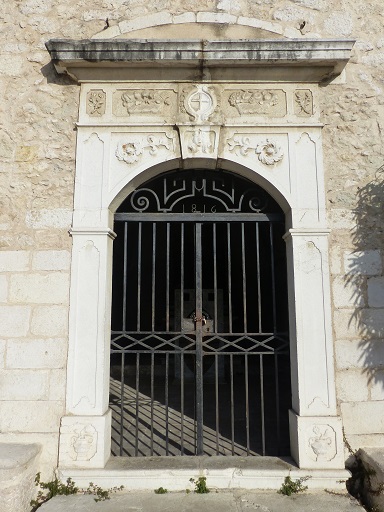 Elévation sud. Porte d'entrée de la chapelle avec un encadrement en pierre de taille calcaire orné.