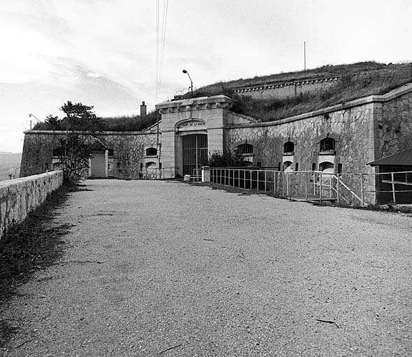 Bâtiment a et entrée du fort. Vue générale depuis la route d'accès. Au deuxième plan, superstructures du bâtiment d (caserne)