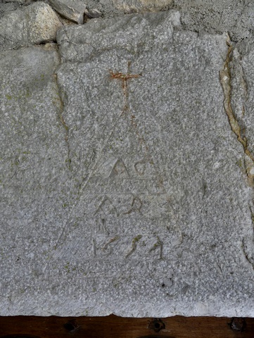 Elévation ouest, deuxième niveau. Porte du logis, cartouche triangulaire surmonté d'une croix latine, avec date gravée (1654) accompagnée d'initiales (A G / A R)