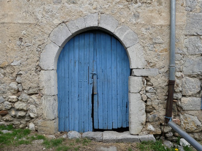 Partie sud, bâtiment occidental. Elévation sud, premier niveau. Porte de l'étable, remployant un encadrement portant une date gravée (1660) accompagnée d'une croix.