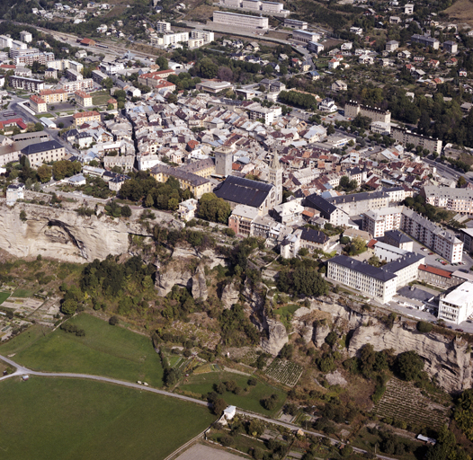 Vue aérienne rapprochée prise du sud-ouest. Falaise du "Roc", ancien front sud de la ville forte.