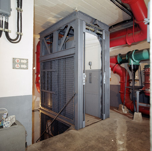 Bloc 1, intérieur : vestibule avec cage d'escalier descendant autour d'un monte-charge, tuyaux de ventilation.