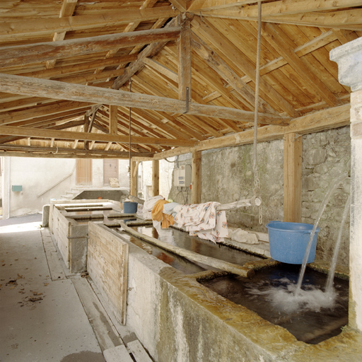 Thorame-Haute. Lavoir public couvert avec bassins alignés sur la place principale du village. La tringle sert toujours à suspendre le linge lavé pour séchage.