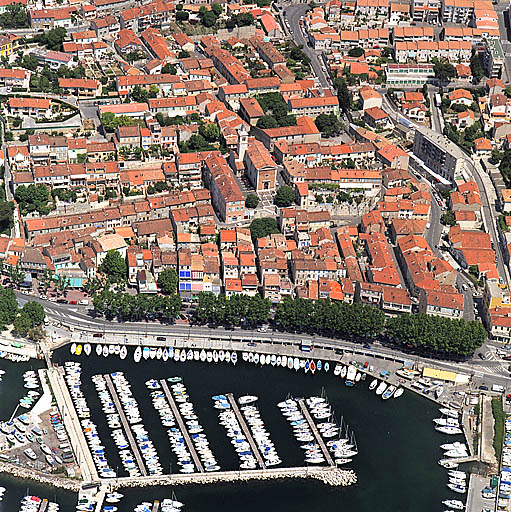 Vue aérienne prise du sud vers le nord, dans l'axe de l'église. Au premier plan, le port et la zone commerçante de la Plage de l'Estaque. A droite, le boulevard Roger-Chieusse.