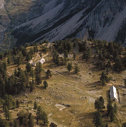 Vue aérienne de la zone-vie prise du sud-ouest. A droite, la baraque H et la citerne. A gauche, les baraques G et K, l'abri du projecteur et la batterie de Cervières. Au fond, la trouée des Aittes et le mur défensif.