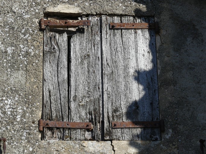 Bâtiment du logis. Pignon ouest, deuxième niveau. Fenêtre occultée par des contrevents à cadre.