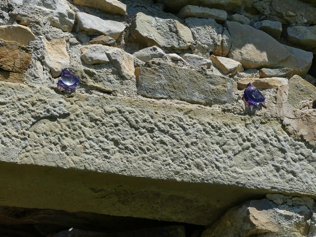 Pignon sud, second niveau. Pieds de verres colorés scellés au dessus du linteau de la porte du logis.